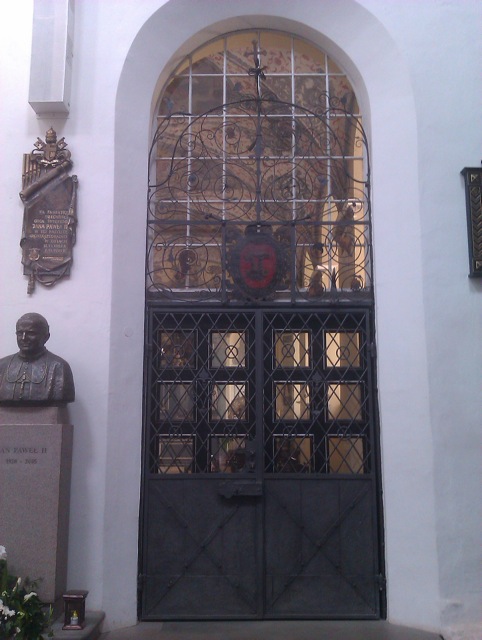 Wejście do kaplicy z krata i herbem Dawida Konarskiego